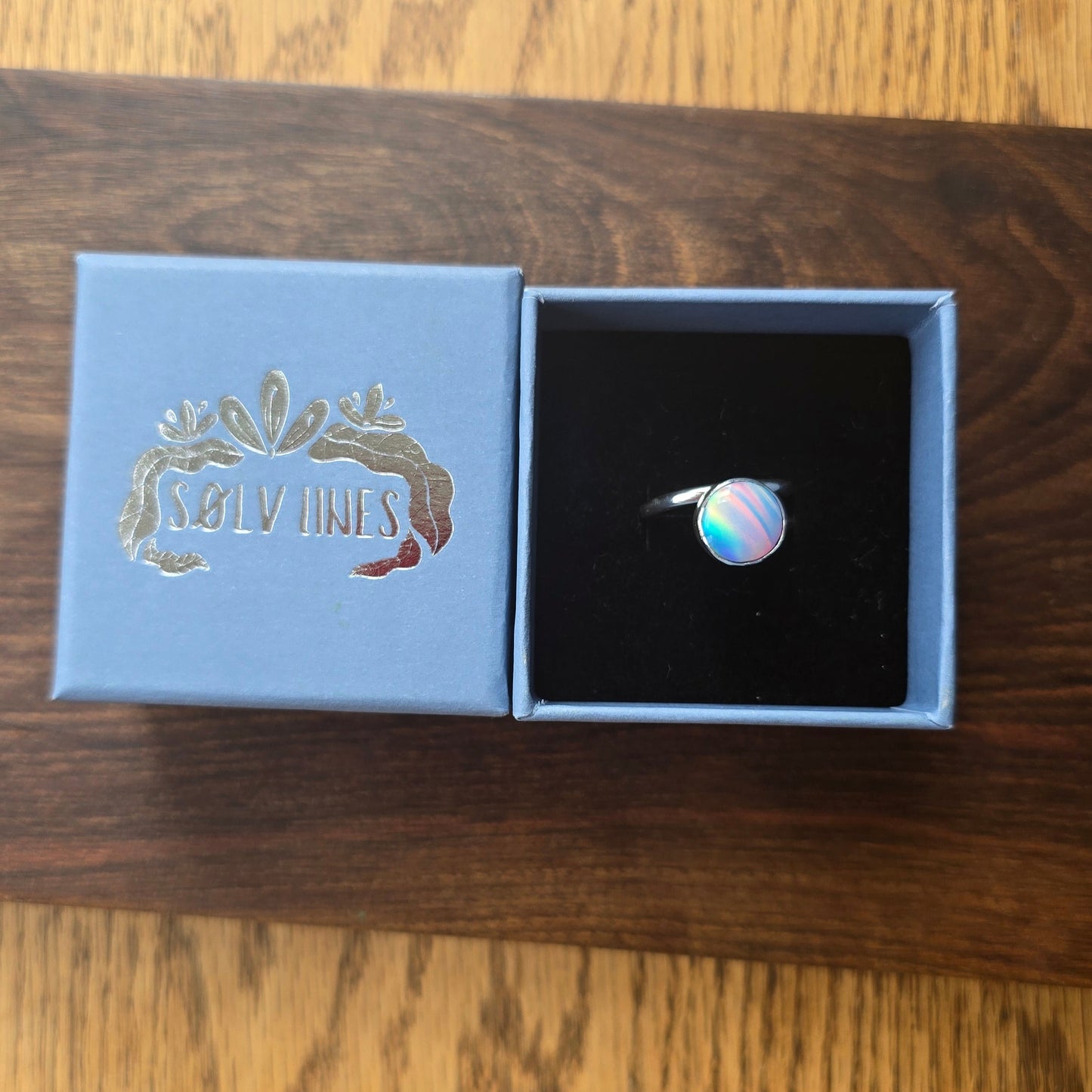 colourful sterling silver ring in a blue box on a wooden surface